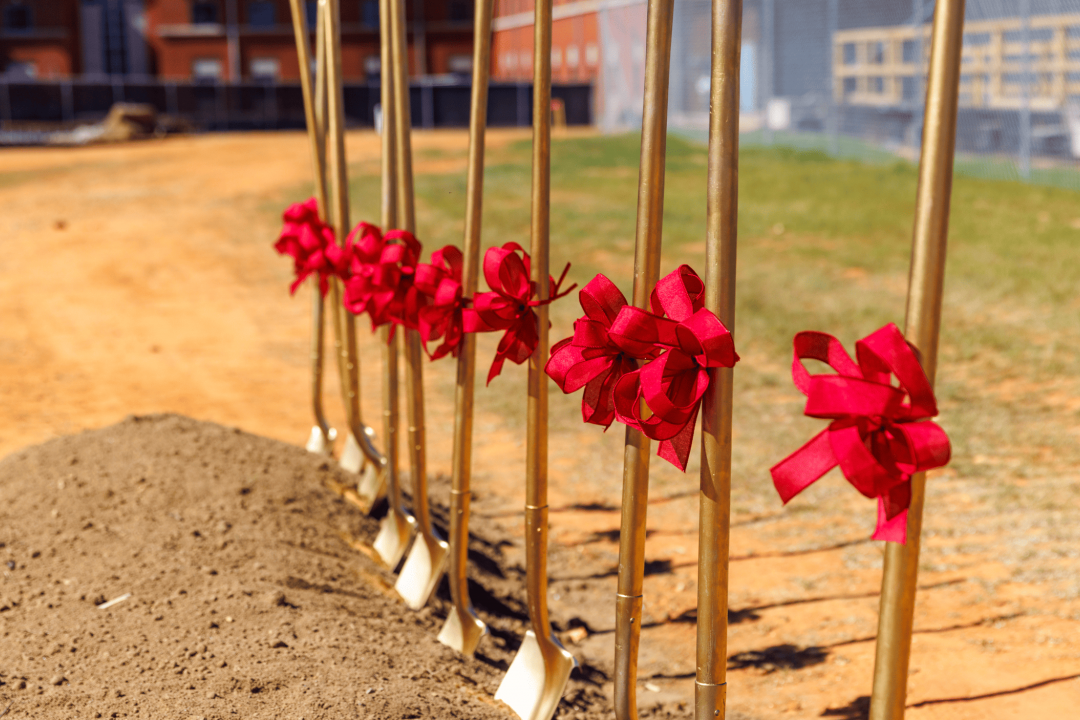 Shovels decorated with red bows standing in a pile of fresh soil